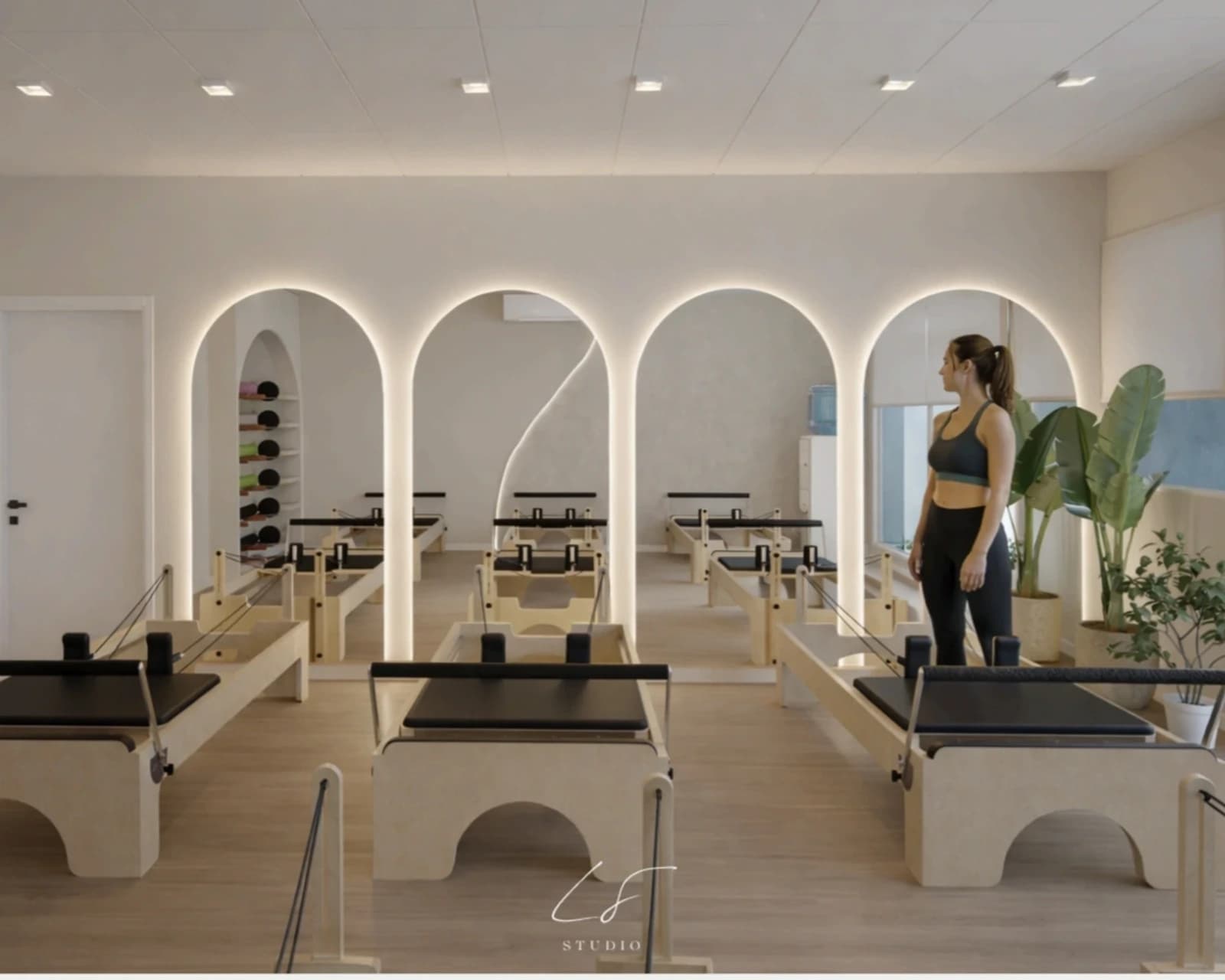 Render del estudio de Pilates de Bienesther con reformers, arcos retroiluminados y ventanales.